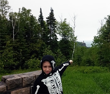 boy in skeleton jacket pointing to whale