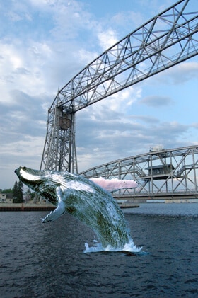 whale jumping in front of aerial lift bridge